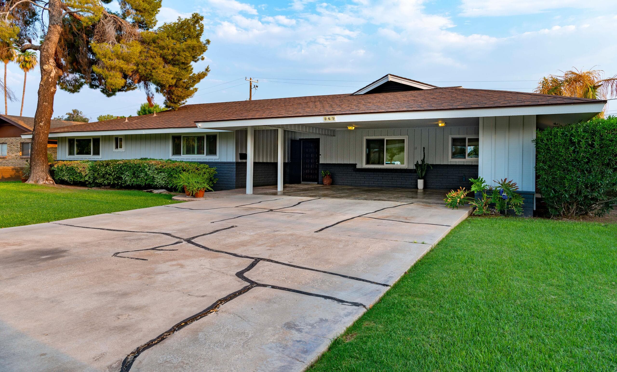Single-storey ranch style house with a wide covered carport and a long concrete driveway